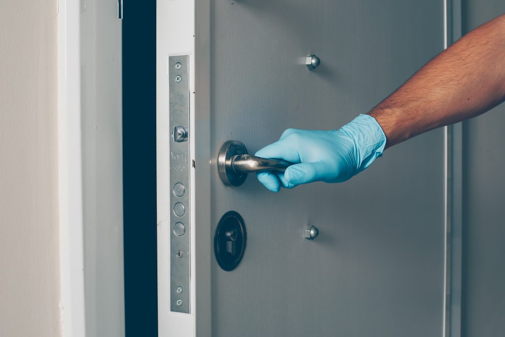 Portrait of a man at room opening the door with hands in gloves coronavirus
